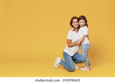 Full Length Happy Woman In Basic White T-shirt Have Fun With Cute Child Baby Girl 5-6 Years Old Hold Hands. Mom Little Kid Daughter Isolated On Yellow Color Background Studio. Mother's Day Love Family