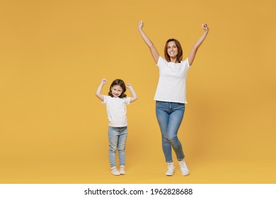 Full Length Happy Woman In Basic White T-shirt Have Fun With Cute Child Baby Girl 5-6 Years Old Hold Hands. Mom Little Kid Daughter Isolated On Yellow Color Background Studio. Mother's Day Love Family