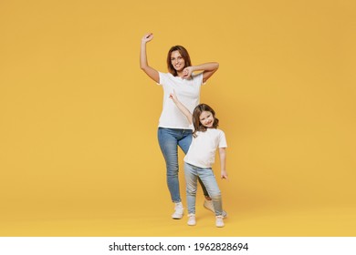 Full Length Happy Woman In Basic White T-shirt Have Fun With Cute Child Baby Girl 5-6 Years Old Hold Hands. Mom Little Kid Daughter Isolated On Yellow Color Background Studio. Mother's Day Love Family