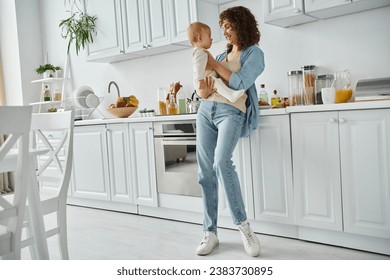 full length of happy woman holding little daughter in spacious modern kitchen with white furniture - Powered by Shutterstock