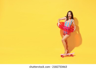 Full length happy young sexy woman slim body wear red blue swimsuit posing with inflatable ring skate isolated on vivid yellow color wall background studio. Summer hotel pool sea rest sun tan concept