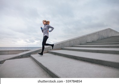 Full length of healthy sports woman running down the stairs. Fitness female workout outdoors. - Powered by Shutterstock