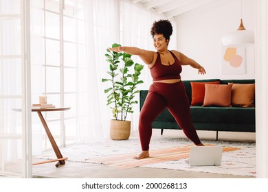 Full length of healthy woman exercising at home watching online video on laptop. Beautiful female in sports wear doing yoga. - Powered by Shutterstock