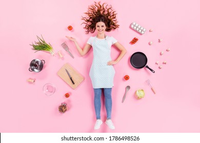 Full Length High Angle Above Flat Lay View Photo Of Pretty Housewife Lady Lying Floor Show Open Arm Fresh Food Wear Kitchen Apron Cooking Utensils Cuisine Isolated Pink Color Background