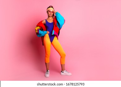 Full length image of 80's Fashion woman over pink background. Beautiful athletic girl in 80s style sportswear, fashionable woman in bright body suit 