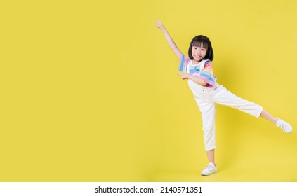 Full Length Image Of Asian Child Posing On Yellow Background