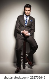 Full Length Image Of A Elegant Business Man Holding His Hands While Sitting On A Stool, Looking At The Camera And Thinking.