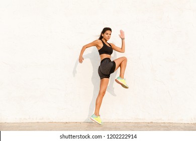 Full length image of energetic woman 20s in sportswear working out and running along wall - Shutterstock ID 1202222914