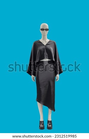 Full length image of a female display mannequin wearing fashionable black suit with blouse and skirt isolated on a blue background