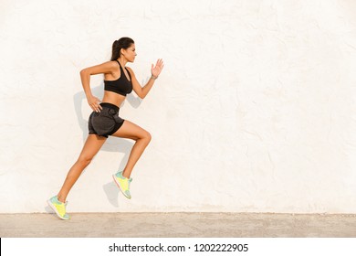 Full length image of fitness girl 20s in sportswear working out and running along wall - Shutterstock ID 1202222905