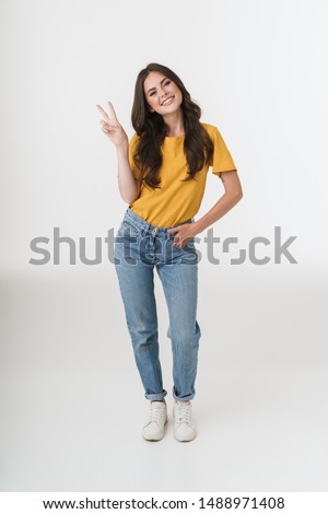 Full length image of gorgeous brunette woman wearing casual clothes smiling and showing peace sign isolated over white background