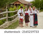 Full length image Happy family with kids in traditional romanian dress in a countryside, park. Father, mother, son and daughters walking outside.