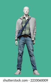 Full length image of a male display mannequin dressed in gray hoodie with zipper, green plaid shirt and blue jeans isolated on green background - Shutterstock ID 2233060009