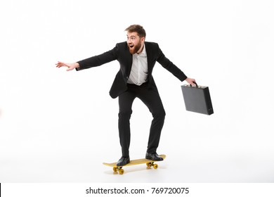 Full Length Image Of Playful Bearded Business Man With Briefcase Riding On Skateboard Over White Background