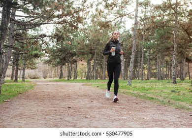 Full Length Image Of Woman Running In Warm Clothes In Autumn Park With Cup Of Water.