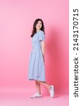 Full length image of young Asian woman wearing blue dress on pink background