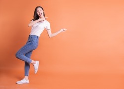 Full Length Image Of Young Asian Woman Posing On Orange Background