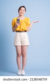 Full Length Image Of Young Asian Woman Using Smartphone On Blue Background