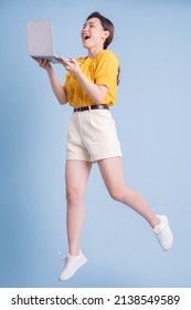 Full Length Image Of Young Asian Girl Using Laptop On Blue Background