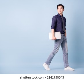 Full length image of young Asian businessman on blue background