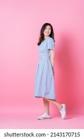Full length image of young Asian woman wearing blue dress on pink background - Shutterstock ID 2143170715