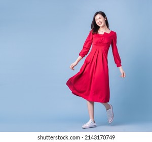 Full Length Image Of Young Asian Woman Wearing Red Dress On Blue Background