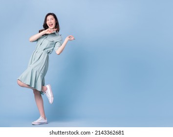 Full length image of young Asian woman wearing dress on blue background - Shutterstock ID 2143362681