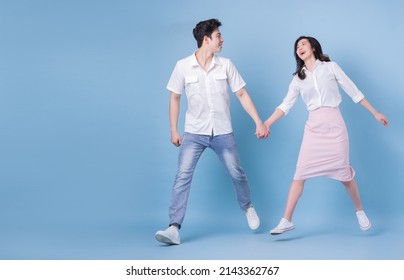 Full length image of young Asian couple on blue background - Powered by Shutterstock