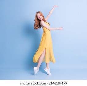 Full Length Image Of Young Asian Woman Wearing Yellow Dress On Blue Background