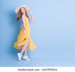 Full length image of young Asian woman wearing yellow dress on blue background - Powered by Shutterstock