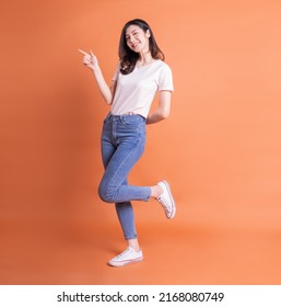 Full length image of young Asian woman posing on orange background - Shutterstock ID 2168080749