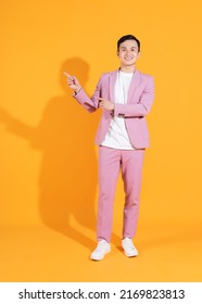 Full Length Image Of Young Asian Man  Standing On Orange Background