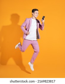 Full length image of young Asian man  standing on orange background - Shutterstock ID 2169823817