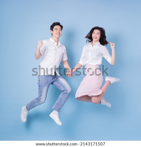 Full length image of young Asian couple on blue background