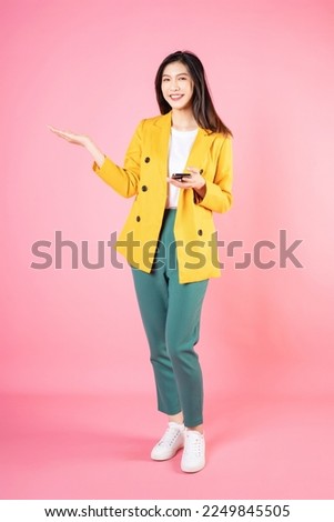 Full length image of young Asian business woman standing on background