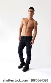 Full length image of a young man with nacked torso in black jeans, looking at camera, isolated on a white background.