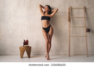 Full length of korean woman in black bikini posing near textured wall in the bathroom - Powered by Shutterstock