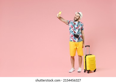 Full length of laughing young traveler tourist man in summer clothes hat doing selfie shot on mobile phone isolated on pink background. Passenger traveling on weekends. Air flight journey concept