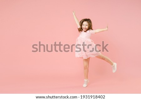 Full length of little kid girl 5-6 years old wears rosy dress have fun dancing fooling around celebrate play isolated on pastel pink background child studio portrait. Mother's Day love family concept