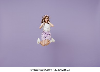 Full Length Little Overjoyed Kid Girl 12-13 Years Old In White Short Sleeve Shirt Do Winner Gesture Hold Face Jumping High Isolated On Purple Color Background. Childhood Children Lifestyle Concept.