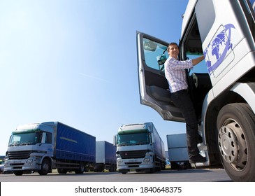 A full length low angle shot of a Truck driver climbing into the cab of a semi-truck on bright sunny day at a loading dock