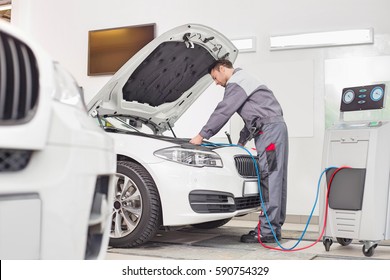Full Length Of Male Engineer Examining Car In Automobile Repair Shop