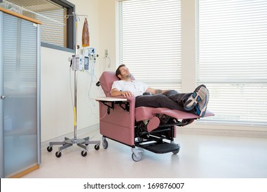 Full Length Of Male Patient Relaxing During Chemotherapy In Hospital Room