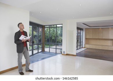 Full Length Of A Male Real Estate Agent Observing New Property