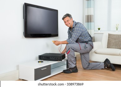 Full Length Of Male Technician Installing TV Set Top Box At Home