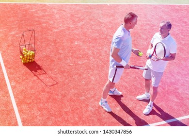 Full length of men talking while standing on tennis court during match