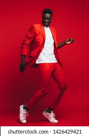 Full Length Od Handsome Young African Man Dancing On Red Background. Man In Stylish Red Outfit Showing Some Dance Moves.