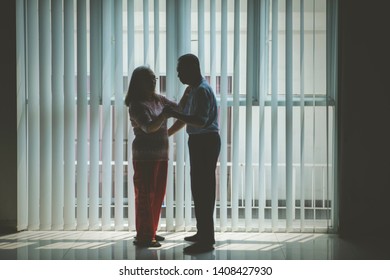 Full Length Of Old Couple Enjoying Leisure Time While Dancing Together Near The Window At Home