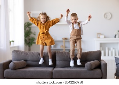 Full length of overjoyed little children brother and sister jumping on sofa, laughing and having fun while playing together at home, kids enjoying carefree leisure time at home - Powered by Shutterstock