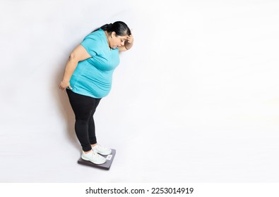 Full length Overweight indian woman shocked to check weight scale on machine isolated over white background. - Shutterstock ID 2253014919